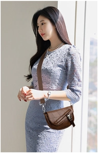 Fashionable dark brown leather saddle bag with wide shoulder strap worn by a model