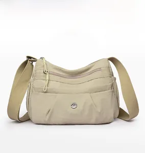 Front view of khaki nylon crossbody bag with multiple zippers and adjustable strap