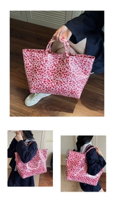Detail shot of a large pink leopard print tote bag with white TOTE BAG text and red spots
