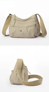Detailed side view of khaki nylon crossbody bag with multi-pocket layers and wide strap