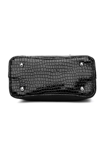 Detail of black glossy crocodile pattern bucket bag base with silver anti-wear studs