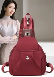 Detail of burgundy waterproof nylon chest bag with metal logo and leather buckle closure