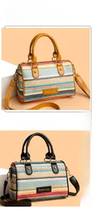 Detailed macro view of woven Boston bag featuring multi-color stripes and leather handles