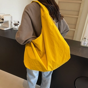 Bright yellow large nylon tote bag for women shown in a modern cafe setting