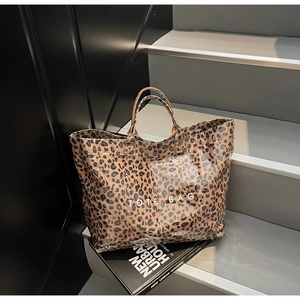 Close-up of translucent leopard print tote bag with white TOTE BAG lettering on urban steps