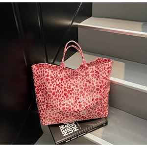 Detail of pink leopard print tote bag with white TOTE BAG text on modern stairs
