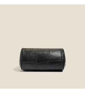 Detail of black cylindrical pillow bag featuring spliced crocodile and lizard textures