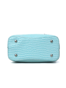Detail view of sky blue bucket bag base with crocodile pattern and silver protective studs