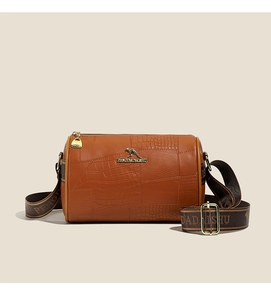 Detail of a brown cylinder crossbody bag featuring crocodile texture and gold kangaroo logo