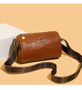 Detail of crocodile embossed leather texture on a brown mini cylinder handbag