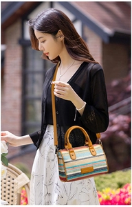 Detail of colorful striped straw bag with brown leather handles and adjustable strap