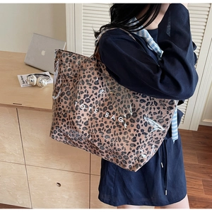 Detail of leopard print tote bag with clear PVC layer and white TOTE BAG text logo