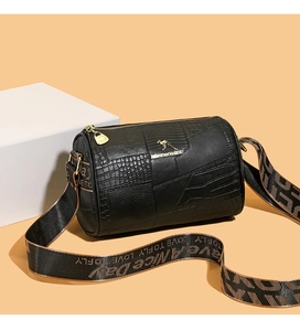 Close-up of black textured leather mini pillow bag with gold logo and wide strap