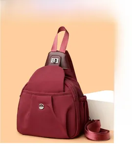 Detail view of burgundy nylon crossbody chest bag with adjustable strap and metal logo