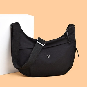 Minimalist black nylon crescent crossbody bag with adjustable strap and metallic LS logo