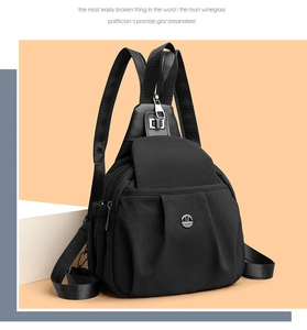 Detail of black nylon backpack with multi-zipper pockets and silver M logo emblem
