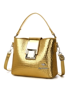Close-up of golden bucket bag with crocodile texture and metallic buckle details