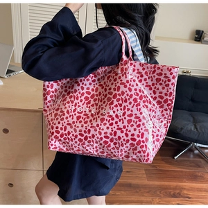 Close-up of a glossy pink leopard print tote bag with white TOTE BAG text print