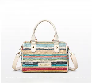 Macro detail of multi-color striped woven straw bag with white leather handles and gold metal