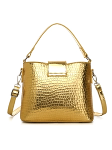 Detail of metallic gold crocodile texture on luxury bucket bag with silver hardware
