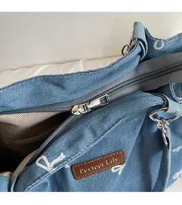 Detailed macro view of the smooth silver zipper and interior lining of the denim tote bag