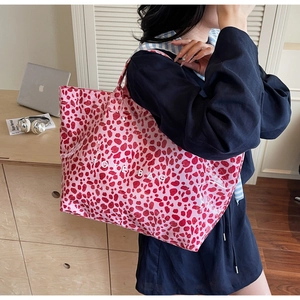 Detailed shot of a stylish pink leopard print PVC tote bag with white text logo print