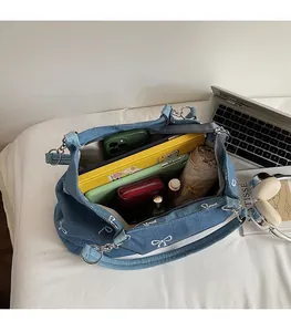 Detail of blue denim tote bag showing interior space with laptop, phone, and accessories