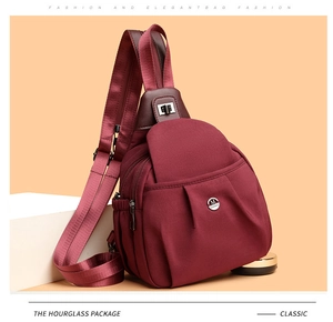 Close-up of wine red nylon crossbody bag with multi-zipper layers and metallic M logo