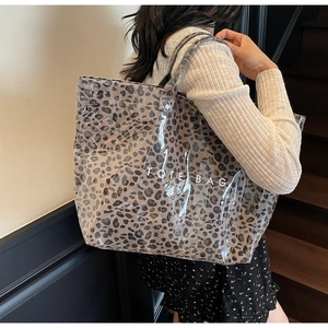 Macro detail of clear PVC tote bag with leopard print liner and white logo text