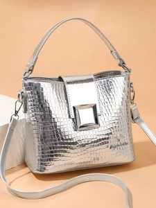 Macro detail of silver crocodile embossed bucket bag with metal buckle and logo