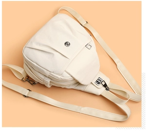 Detail showing high-density canvas texture and multiple zippers of the beige chest bag