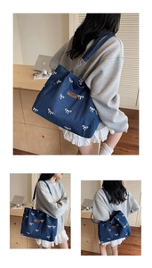 Detail of blue denim tote bag with white bow pattern and silver chain shoulder strap