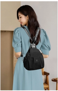 Side view of a black oxford cloth backpack on a model showing adjustable straps and pockets