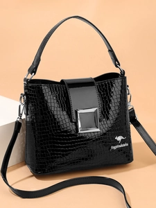 Detail of black crocodile embossed patent leather bucket bag with silver metal buckle