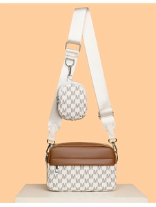 Detail der trendigen Umhängetasche mit weißem M-Muster und runder Mini-Tasche am Gurt