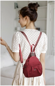 Detailed view of deep red nylon backpack worn as a chest bag in a modern setting