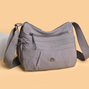 Grey nylon crossbody bag with multi-zipper compartments and adjustable wide strap