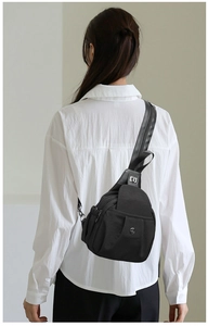 Detail view of black nylon crossbody sling bag with multi-layer zipper pockets and flap
