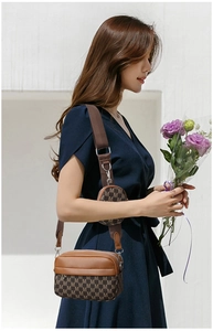 Detail einer braunen Umhängetasche mit M-Muster und abnehmbarer runder Münztasche am Gurt