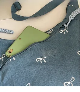 Detail der blauen Jeans-Umhängetasche mit Schleifenmuster und Reißverschluss-Seitentasche