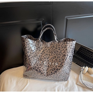 Leopard print tote bag detail showing glossy texture and TOTE BAG lettering in room setting