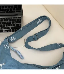 Detail des verstellbaren Denim-Gurts und Metallschnalle der Tasche mit Schleifenprint