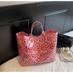 Detail of pink leopard print tote bag featuring glossy finish and white TOTE BAG text
