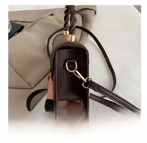 Detail of golden hardware hook and woven handle on vintage dark brown crossbody bag