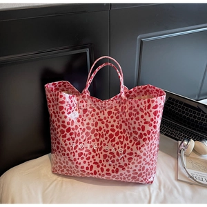 Detail of pink leopard print tote bag with white TOTE BAG text on glossy waterproof fabric