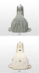 Close-up of pleated nylon chest bags in gray and off-white with metal logo details
