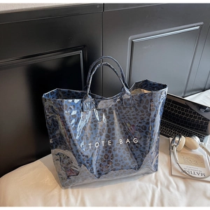 Detail of blue leopard print tote bag with white TOTE BAG text on a white bed