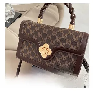 Detail of retro brown crossbody bag with M-pattern embossing and golden flower lock