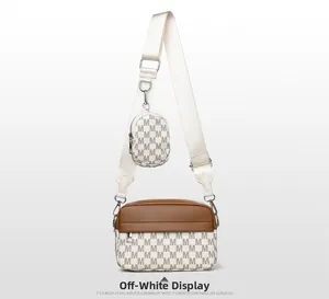 Detail der cremefarbenen Umhängetasche mit Monogramm, kleiner Münztasche und Gurt