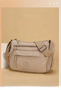 Detail view of beige nylon crossbody bag with multiple zipper pockets and wide strap